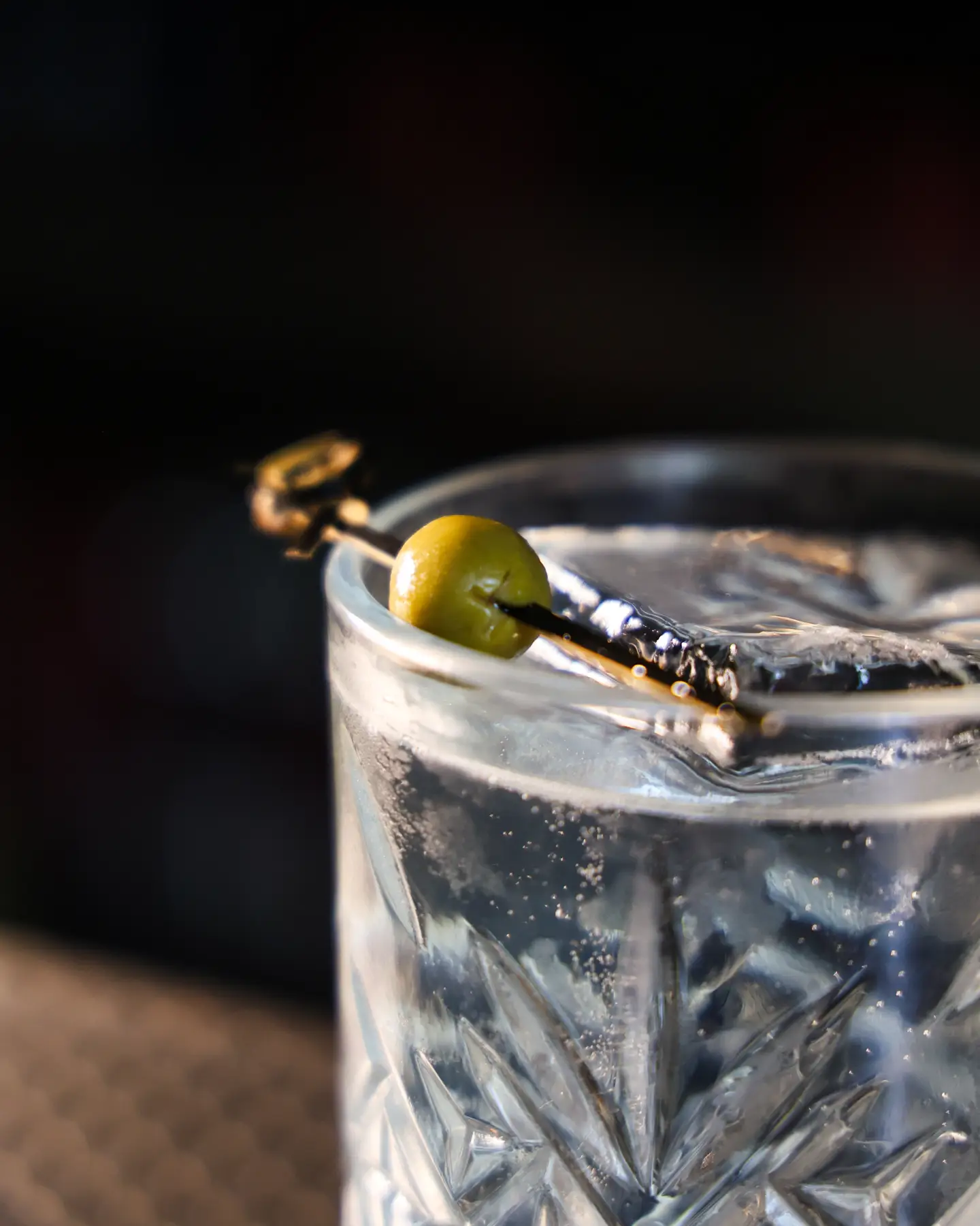 Detalle de un coctel transparente con aceituna