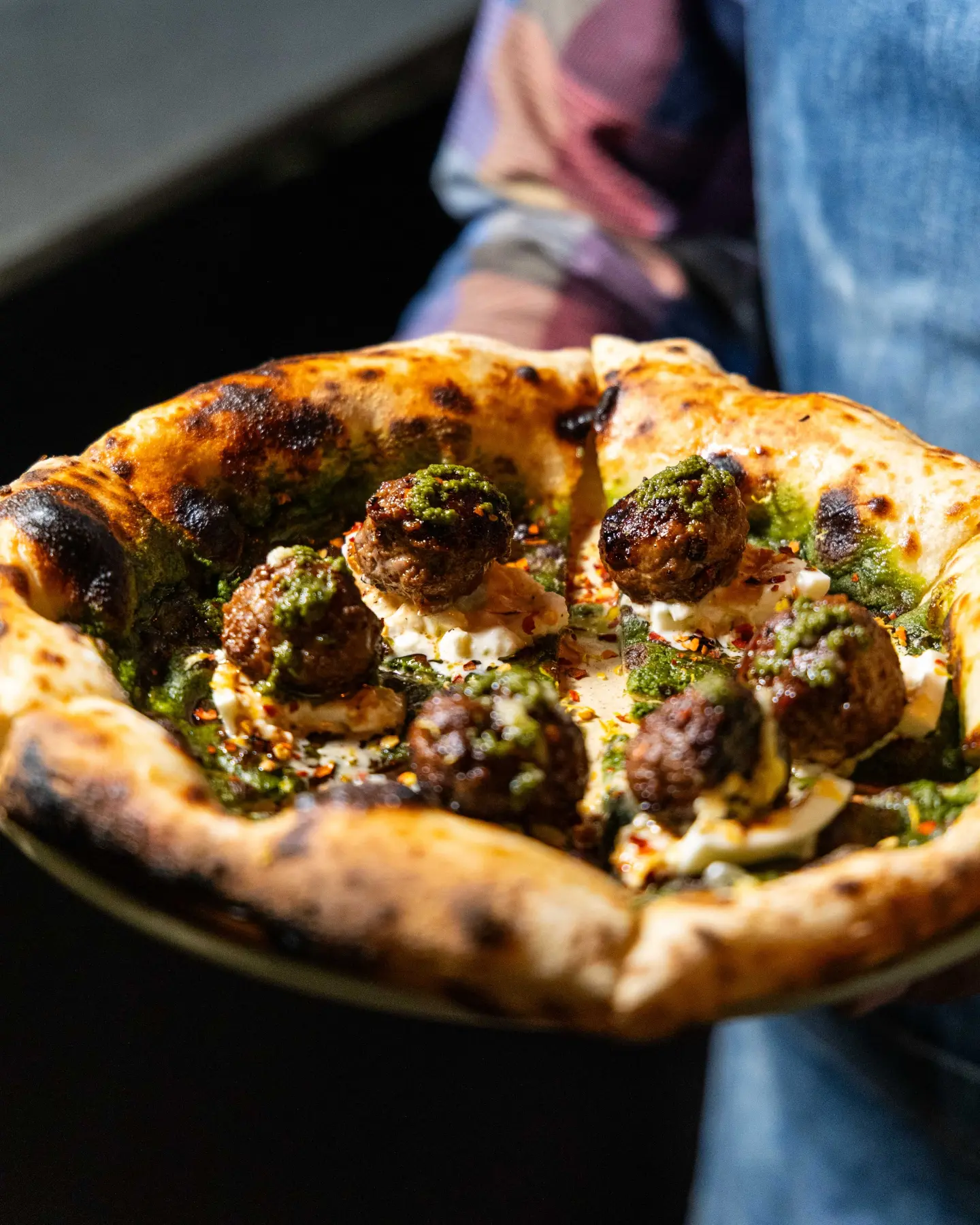 Pizza de borde tostado sostenida frente a la cámara